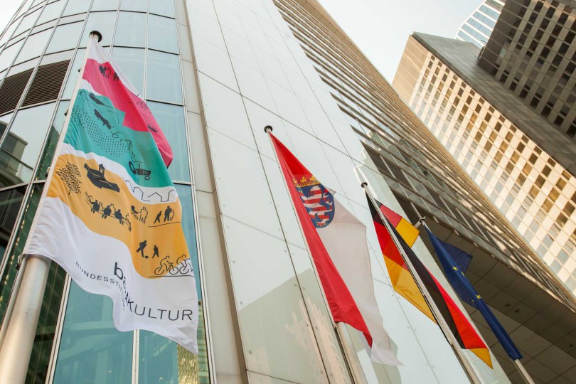 Flagge der Baukulturwerkstatt vor dem Hochhaus der Commerzbank